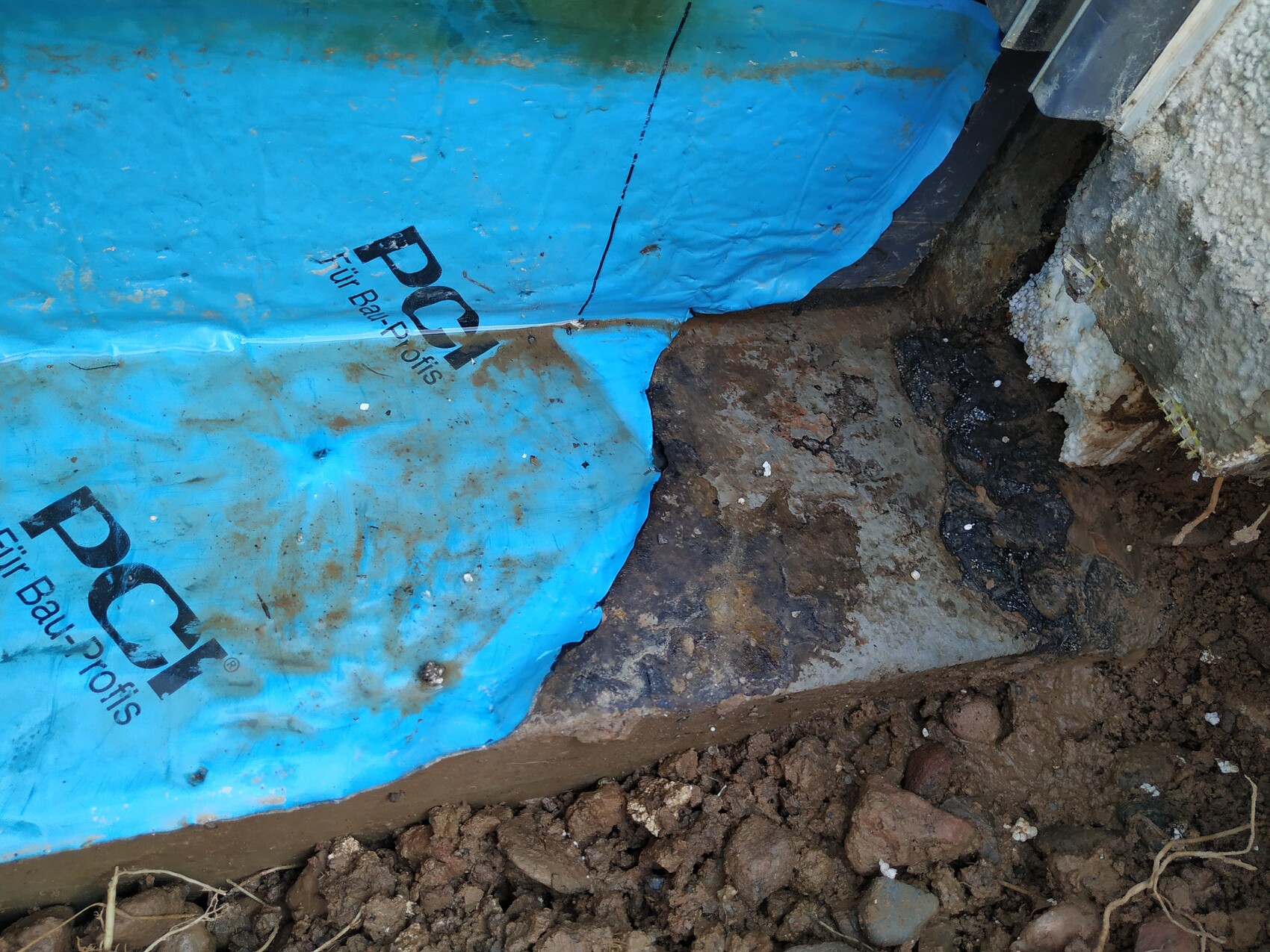 Baugrube und Fundamentbereich mit blauer Abdeckplane auf Baustelle