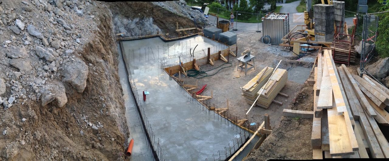 Baustelle mit Graben, Fundamentform, Bewehrung und Holzbaustoffe für Rohbau.