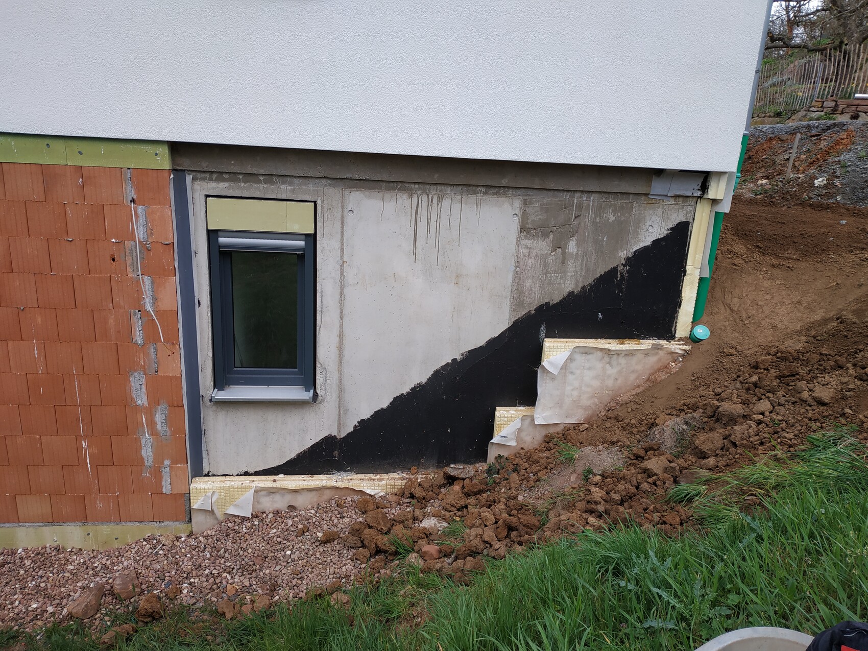 Kellerfundament mit Abdichtung, Fenster und Baugrube bei Neubau