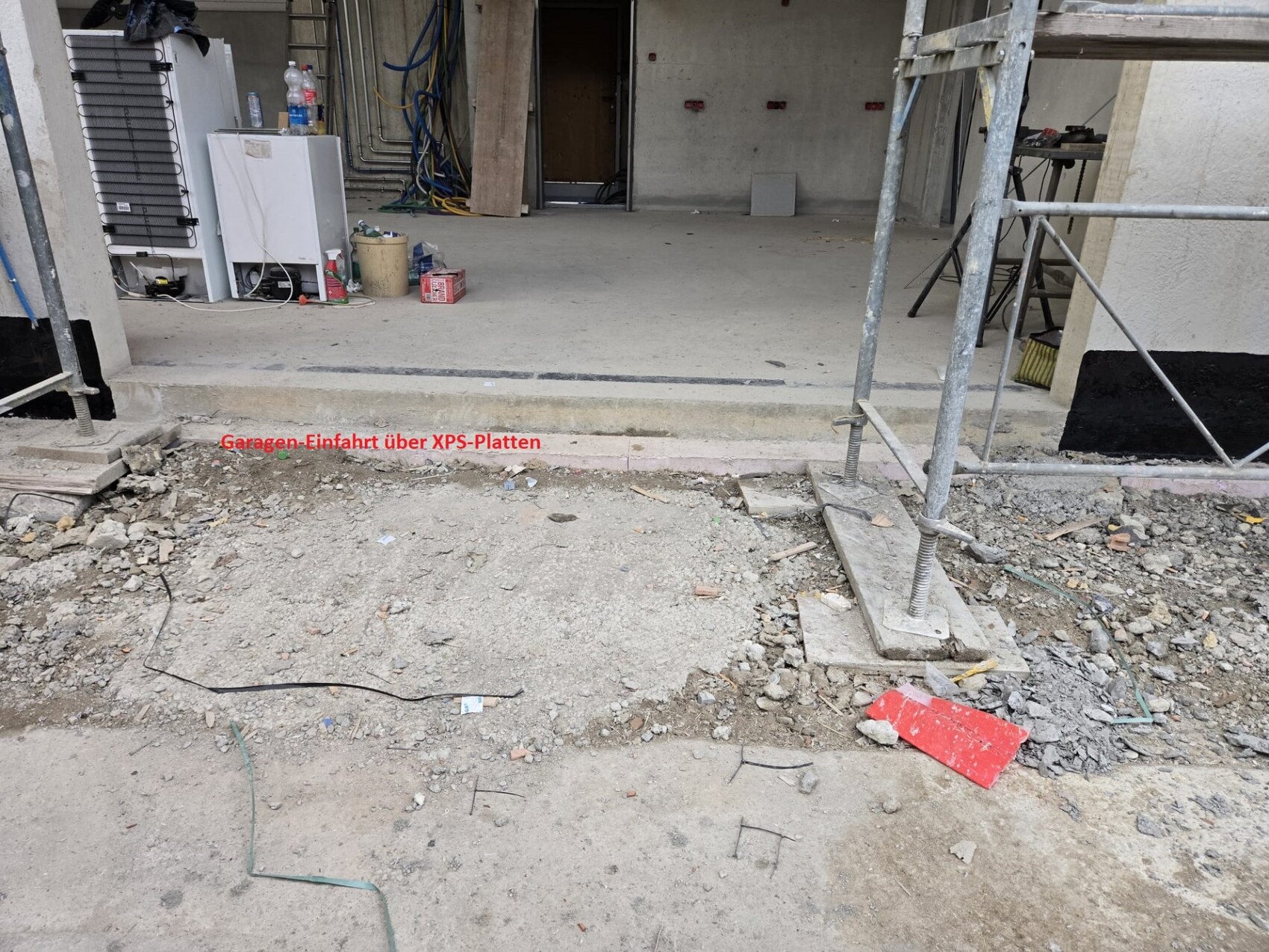 Baustelle am Gebäudeeingang mit Gerüst, offener Rohbau und Erdarbeiten vor Garage