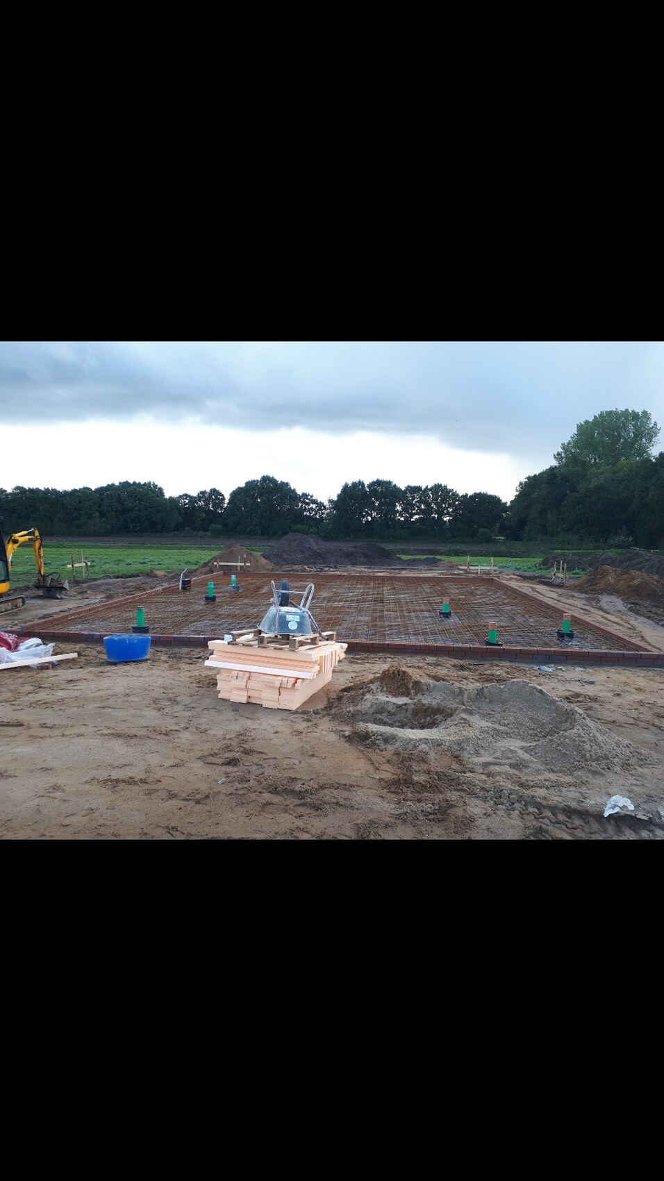Baustelle mit Fundament-Bewehrung, Holzbohlen und Sandhaufen