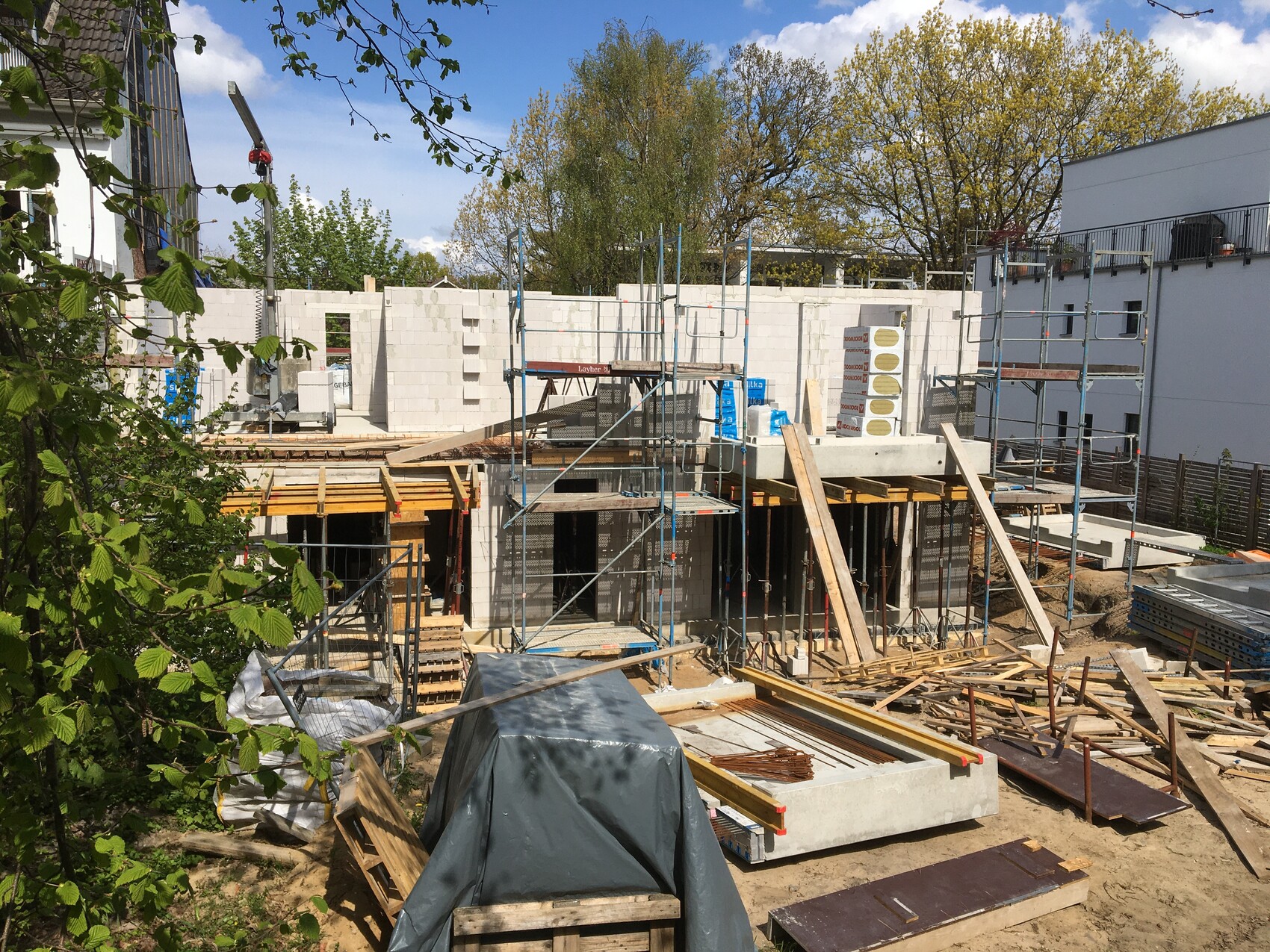 Baustelle mit Rohbau, Gerüst und Baumaterialien auf einem Bauplatz