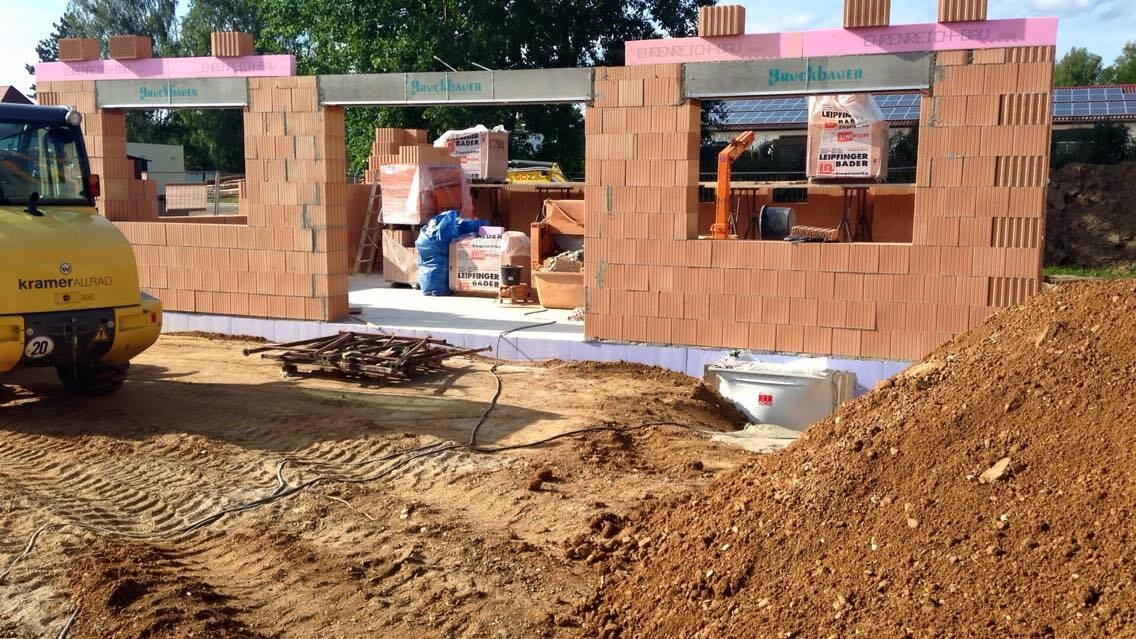 Baustelle mit Rohbauziegelwaenden, Baugeraeten und Erdmassen auf Gelände