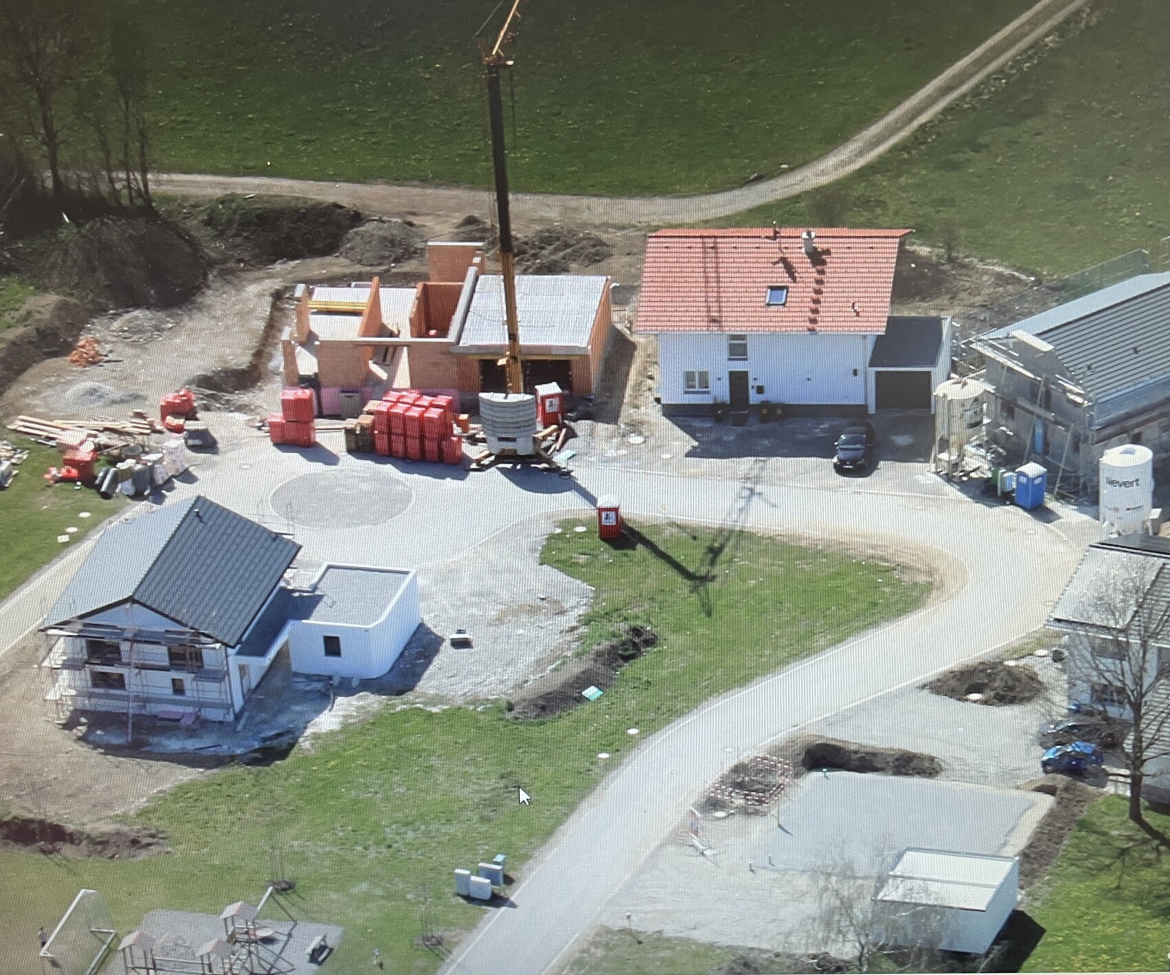 Luftaufnahme einer Baustelle mit Rohbau, Fundamentarbeiten, Kran und Baumaterialien