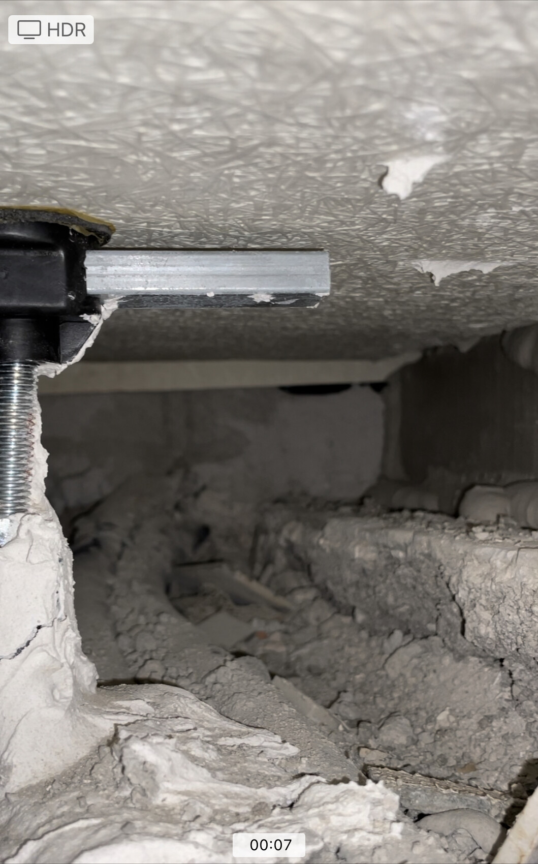 Rohbau-Szene mit Abbruchresten, Putzbruch und Metallhalterung in der Wand.