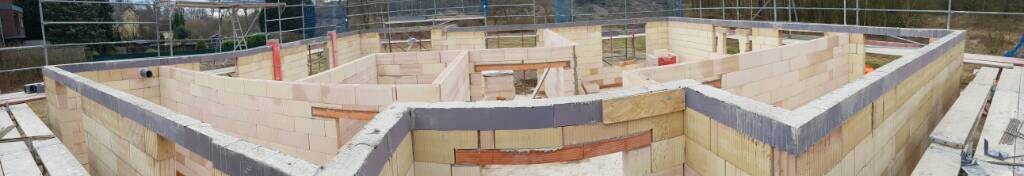 Baustelle mit Bruchsteinmauern im Rohbaufundamentbereich, Baufortschritt sichtbar