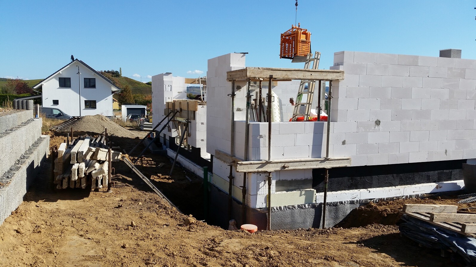 Baustelle mit weißen Porenbetonblöcken, Gerüst und Fundamentarbeiten