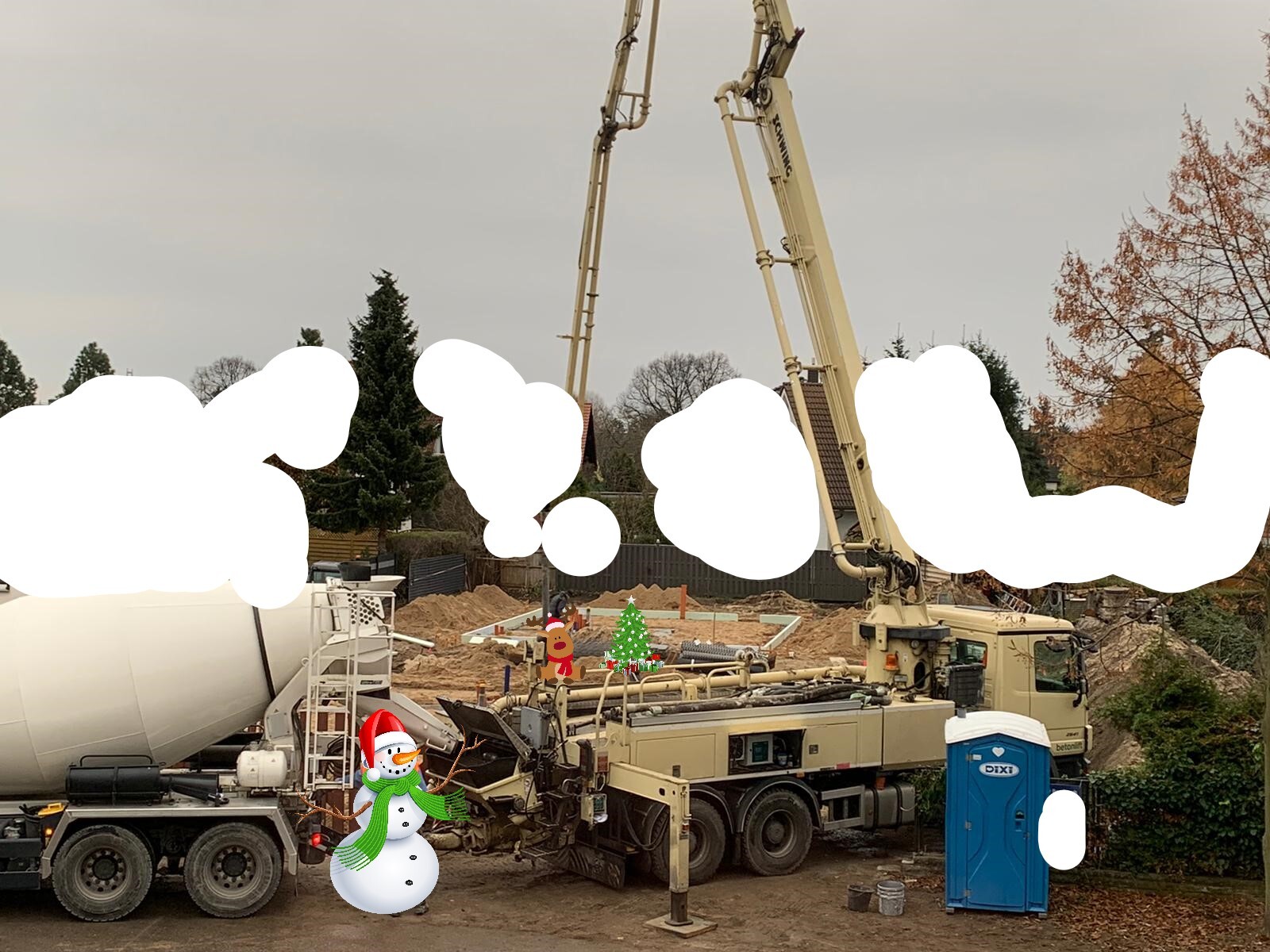 Große Betonpumpen-LKW auf Baustelle, rechts Porta-Potti, vorne Schneemann mit Weihnachtsbaum-Deko.