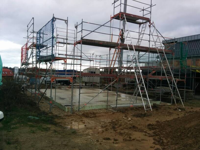 Baustelle mit Stahlgerüst, sichtbarer Fundamentplatte und unbefestigtem Boden