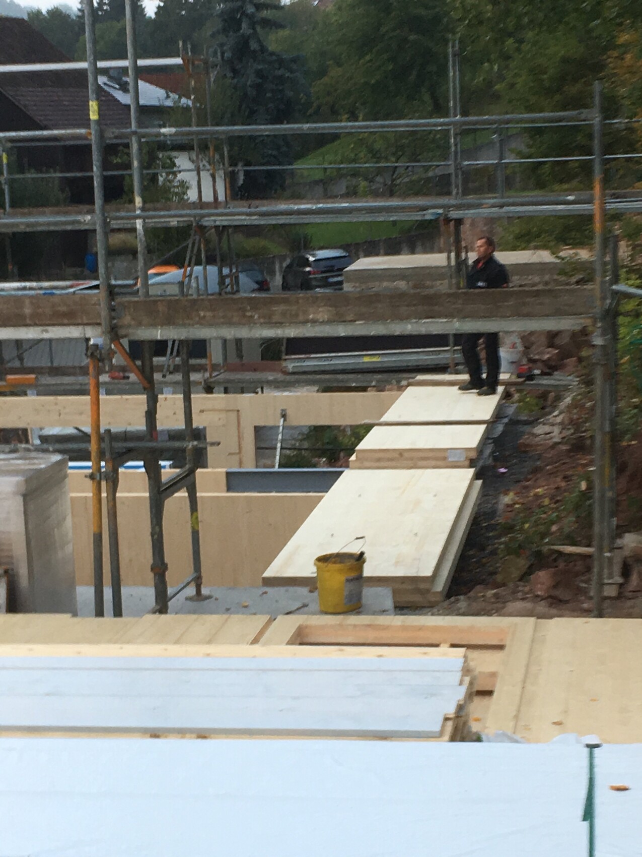 Baustelle mit Gerüst und Holzbohlen; Mann steht auf einer Holzplattform.