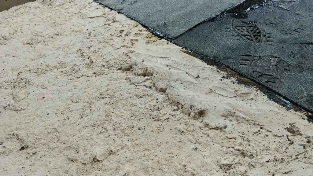 Baustellenboden mit Sand und Asphaltbelag, sichtbare Untergrundarbeiten