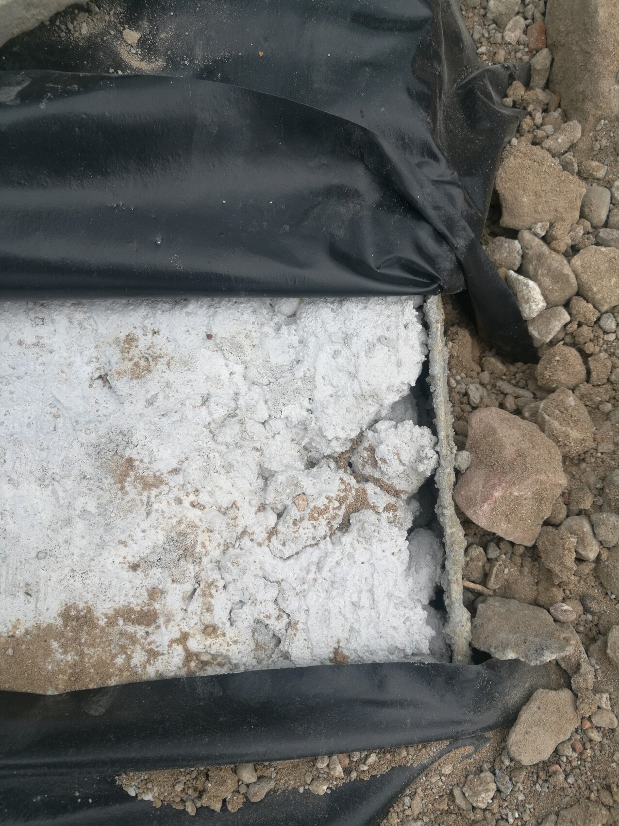 Rohbaufundament aus grobem Beton mit schwarzer Abdeckfolie auf Baustelle