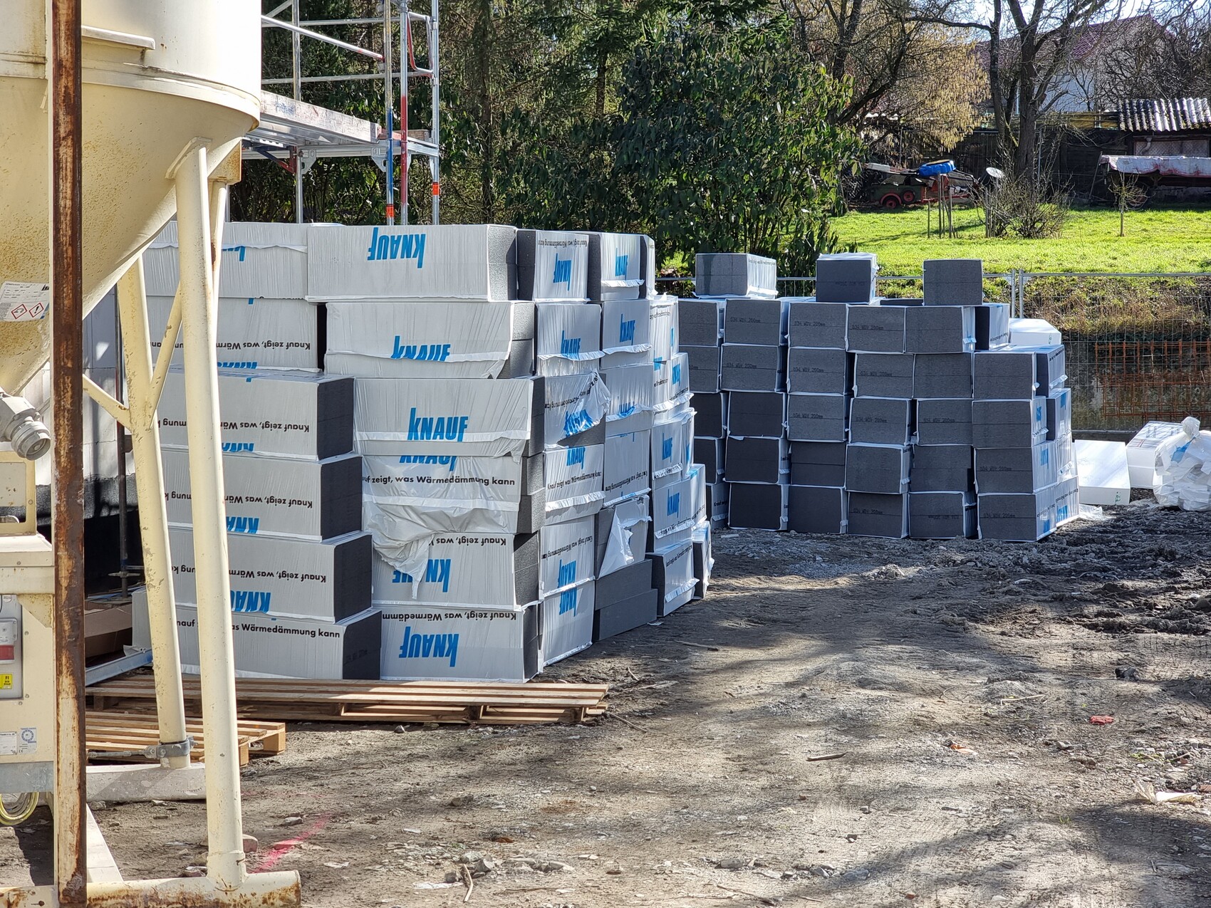 Baustelle mit gestapelten Dämmplatten (Knauf) und grauen Steinblöcken im Freien