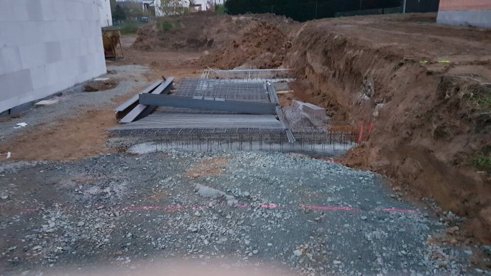 Aushub einer Baugrube mit Bewehrungsstahl und Betonformen auf einer Baustelle.