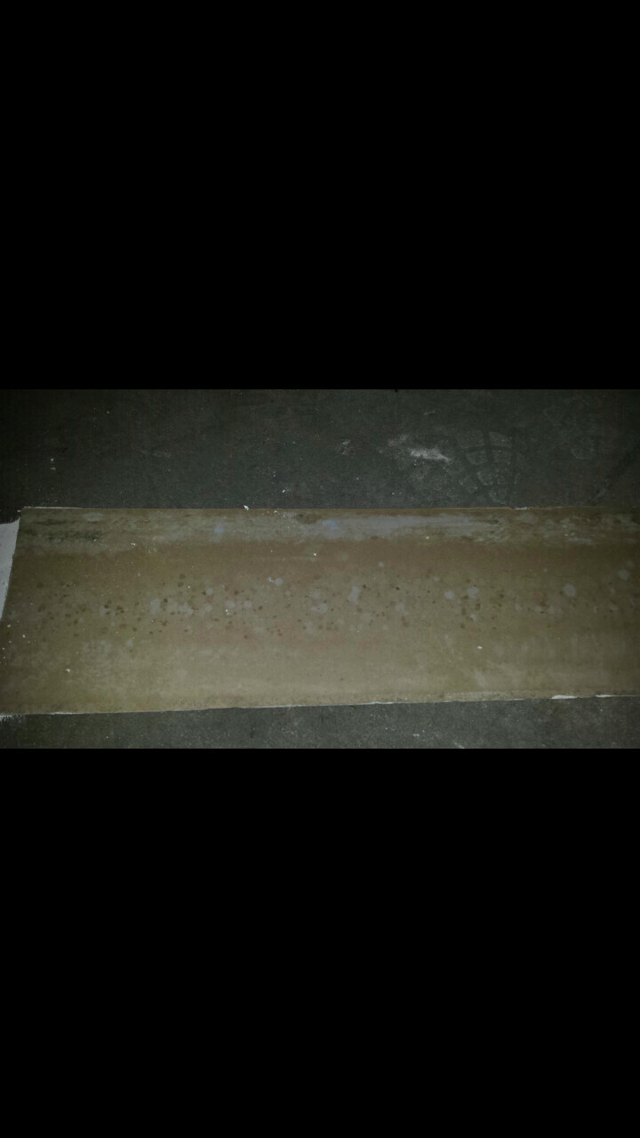 Lange braune Platte liegt auf dunklem Baustellenboden, Hinweis auf Rohbau und Fundament