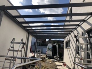 Baustelle mit offener Dachkonstruktion, Gerüst und Terrassenwand.