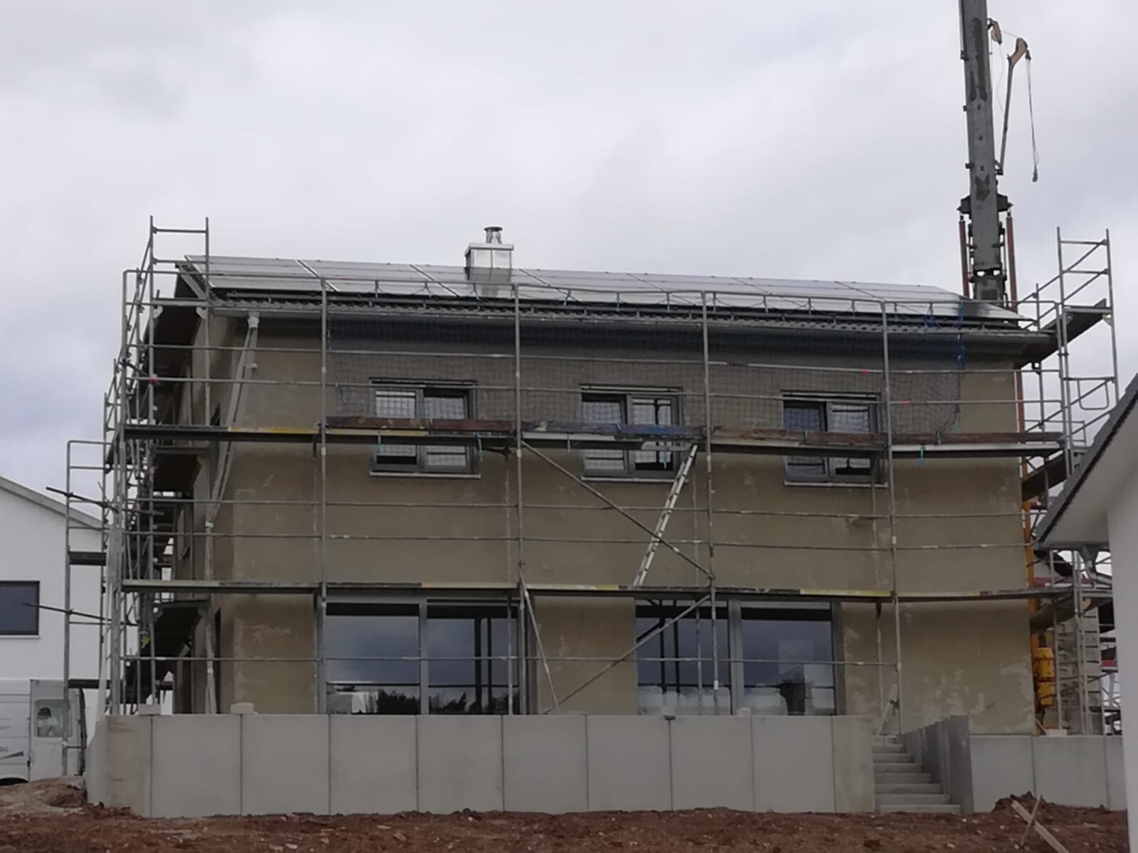 Zweistöckiges Haus mit Gerüst umgeben; Baustelle, Bauarbeiten und Fensterfronten sichtbar.