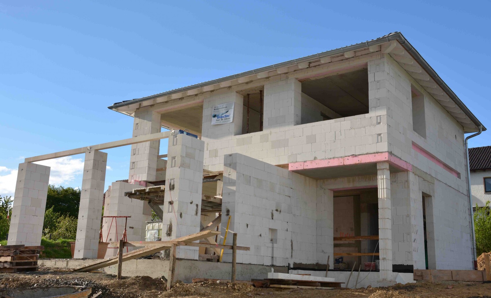 Rohbau eines zweistöckigen Hauses aus Betonblöcken mit offenen Fensteröffnungen und Holzgerüsten