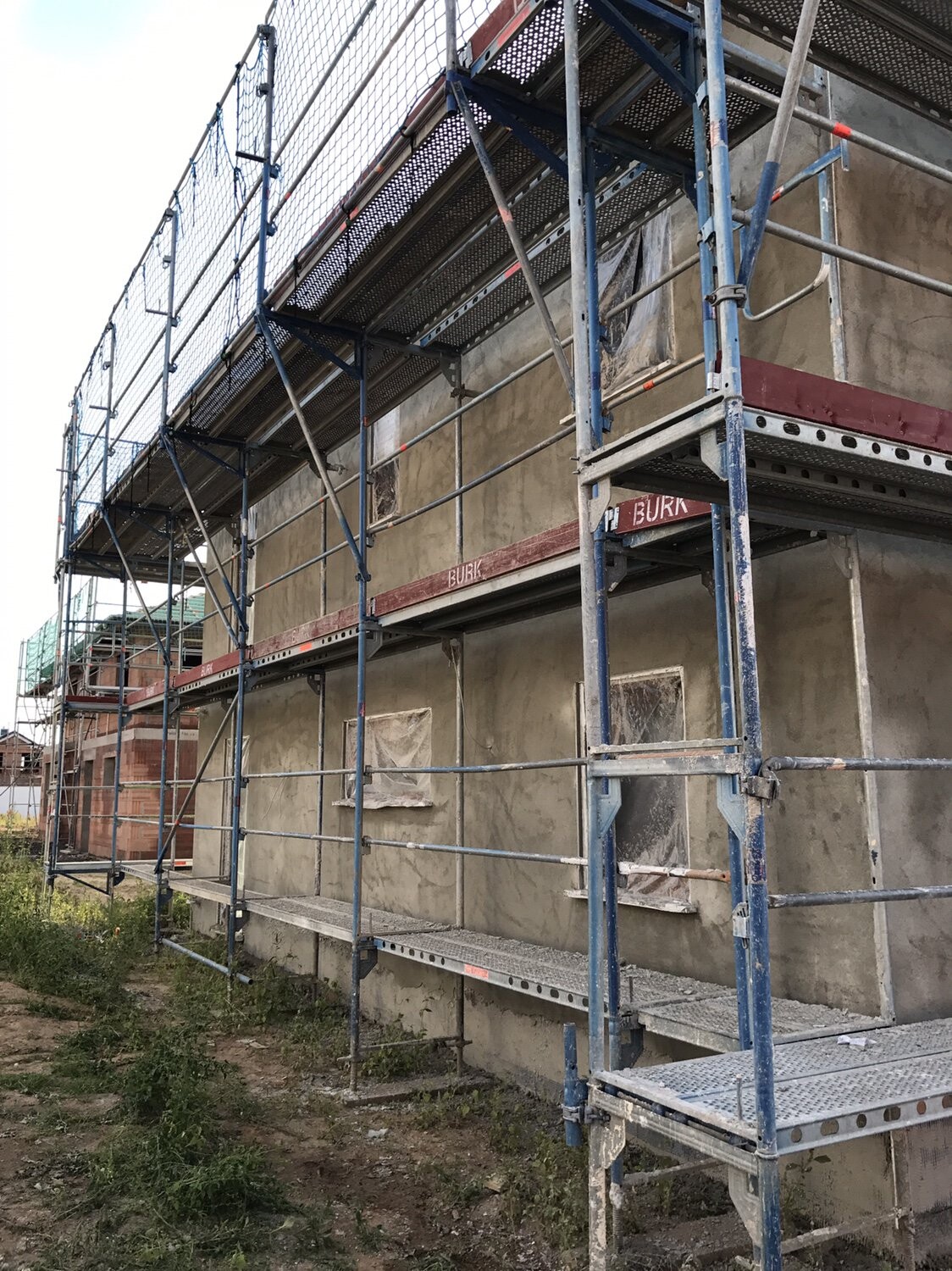 Baustelle mit blauer Gerüstkonstruktion um Gebäude, Rohbau-Außenansicht