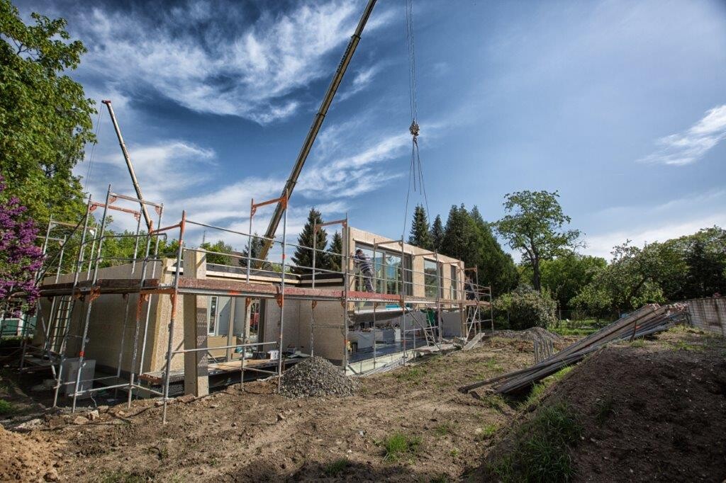 Rohbau eines Einfamilienhauses mit Gerüst und Kran auf der Baustelle