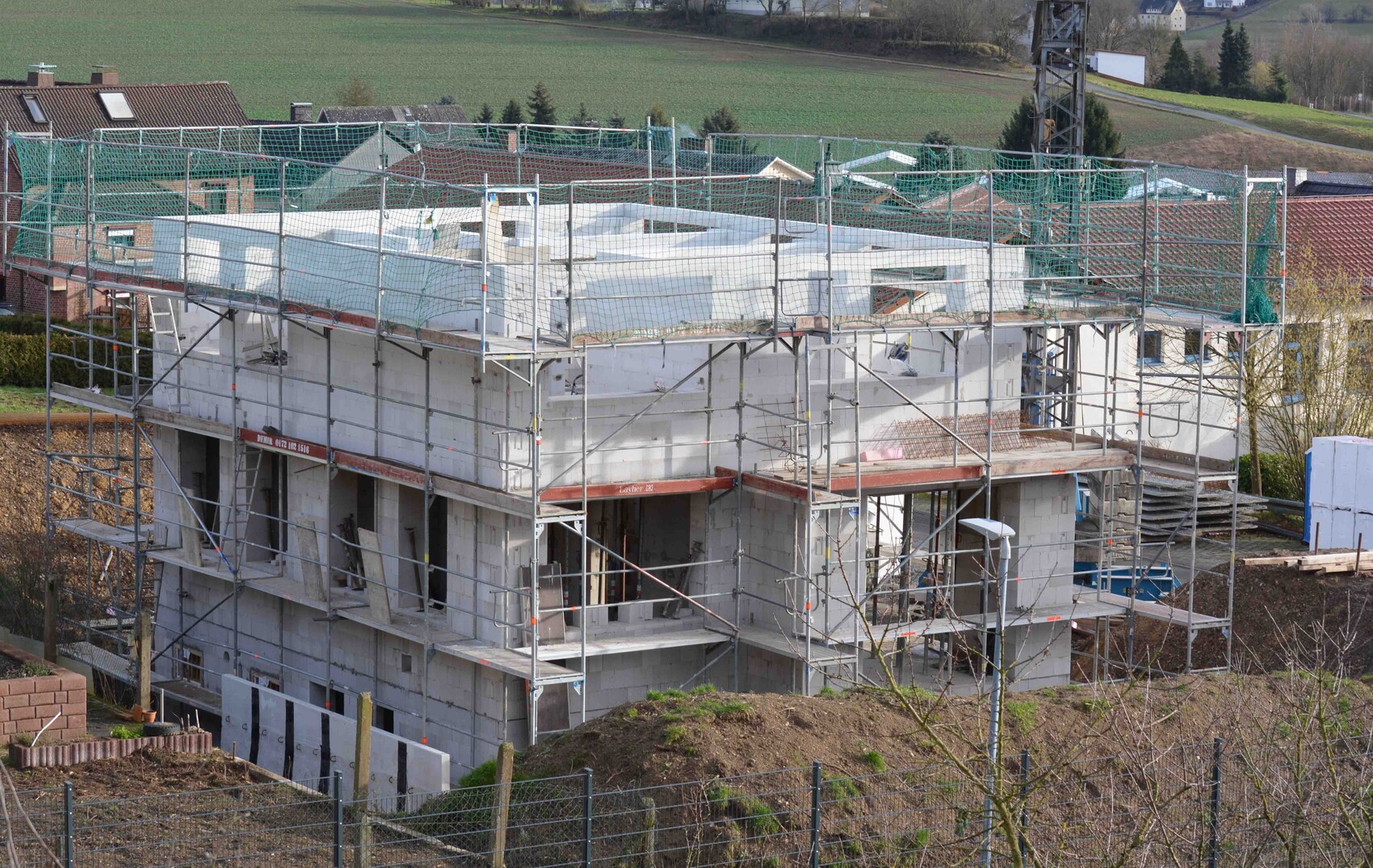 Mehrstöckiges Haus im Rohbau mit Gerüst auf Baustelle