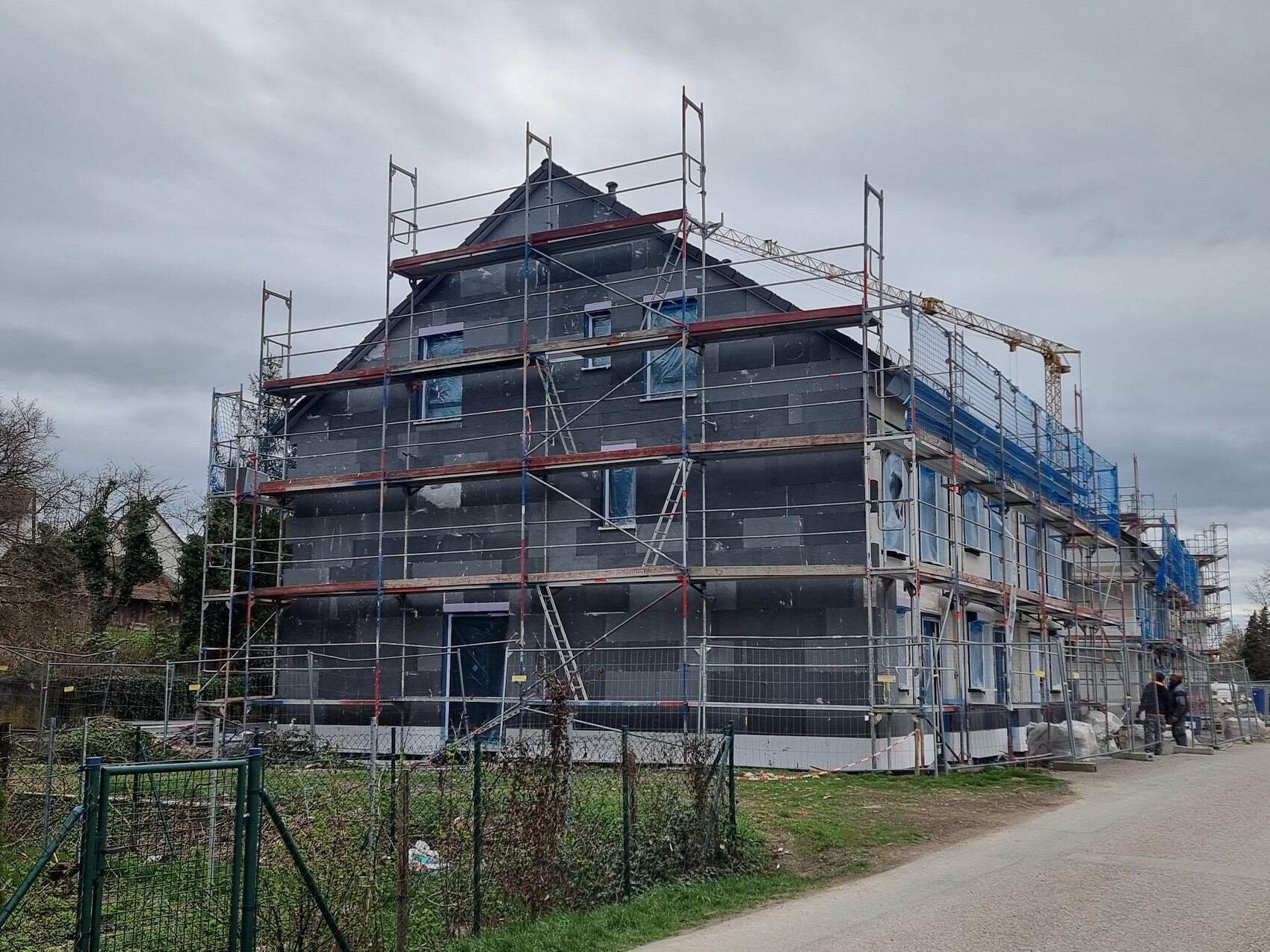 Mehrstöckiges Haus unter Gerüstbau mit schwarzer Fassadenhaut