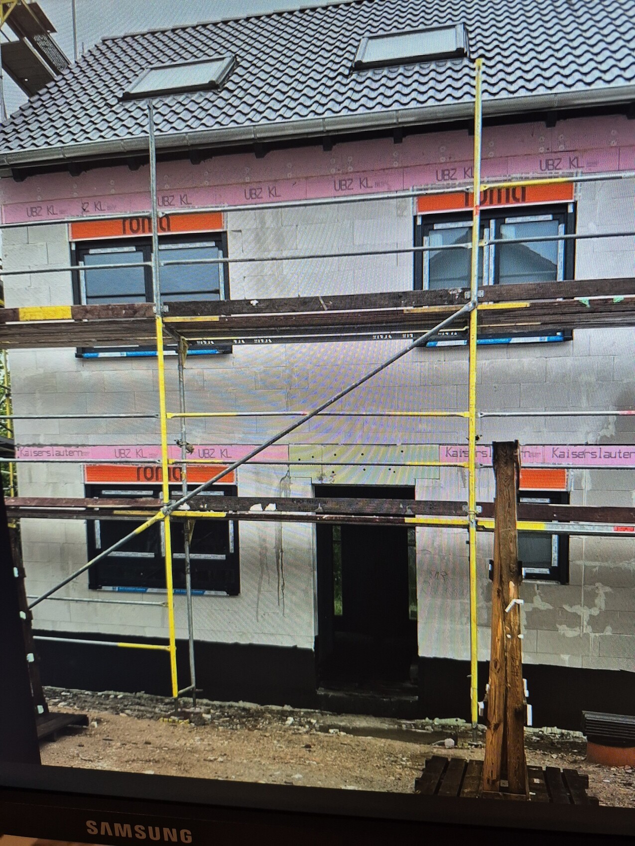 Unfertiges Haus mit Gerüst und Dacharbeiten auf einer Baustelle