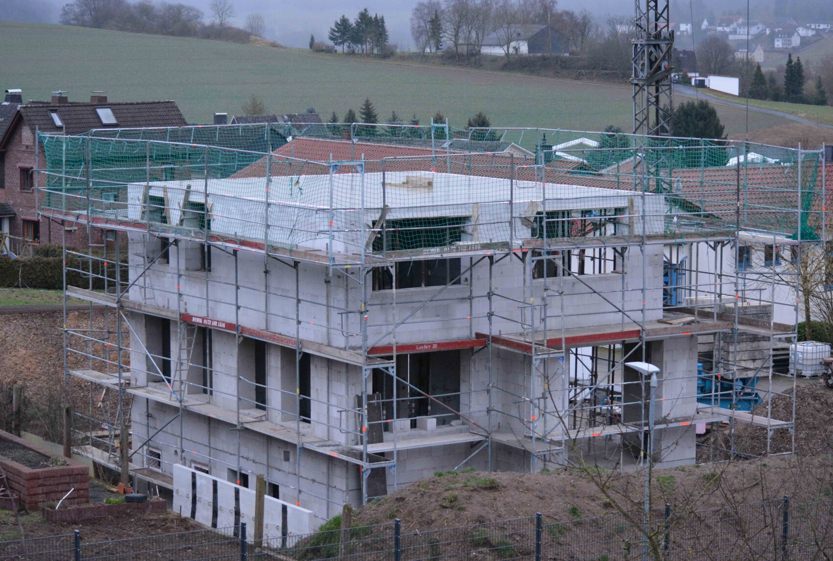 Mehrstöckiger Rohbau mit Gerüsten und Baugeräten auf einer Baustelle