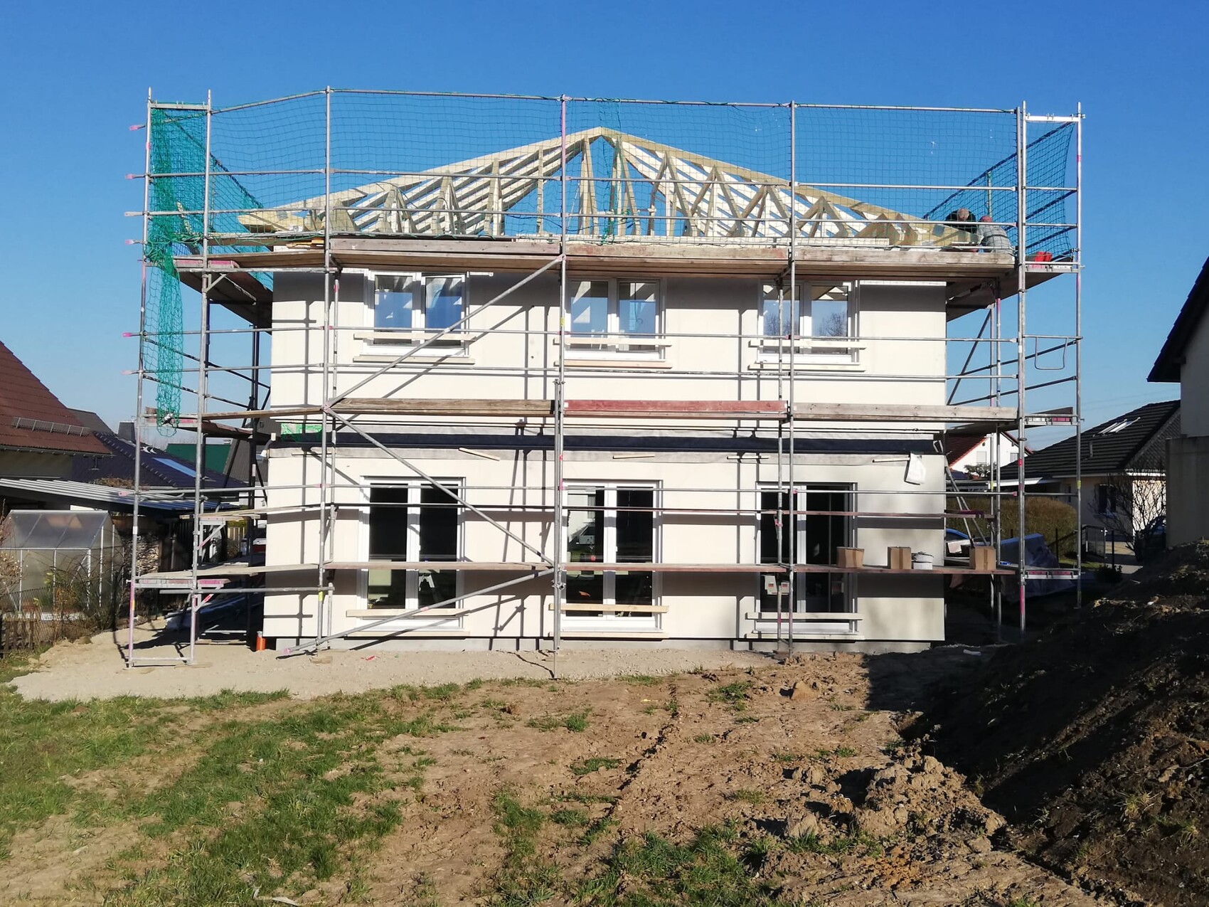 Zweistöckiges Haus unter Gerüstbau mit sichtbarer Dachkonstruktion und Bauarbeiten im Freien
