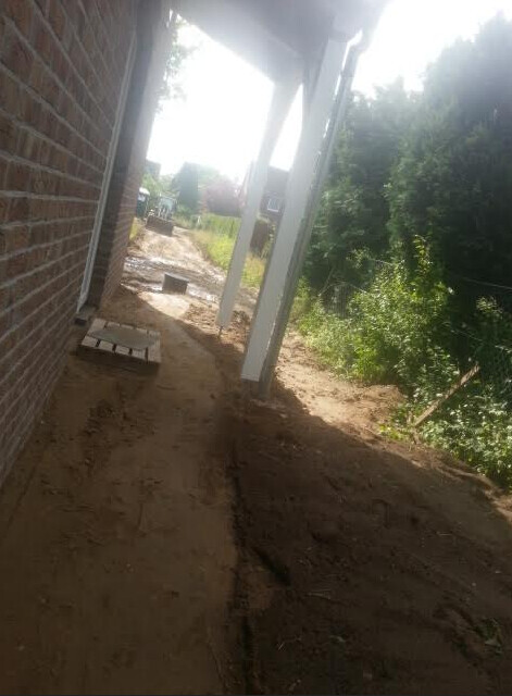 Baustelle am Haus: Erde, Säulen und Baufortschritt außerhalb der Wand
