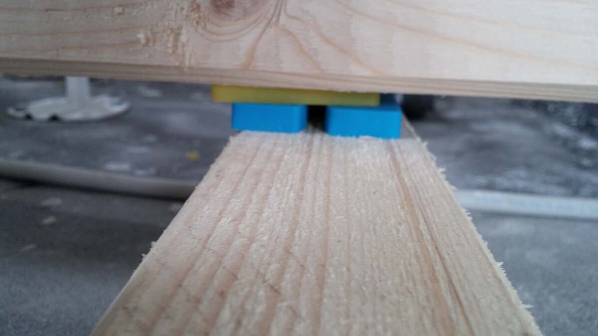 Holzplanke ruht auf blauen Abstandshaltern während Rohbauarbeiten