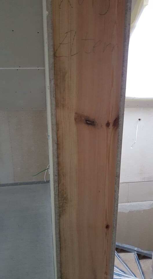 Holzbalken im Rohbau zwischen Betonwand und Gipskartonplatten im Innenbereich