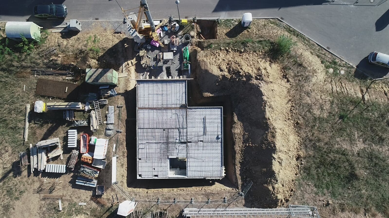 Luftbild einer Baustelle mit Rohbaufundament und Baumaterialien