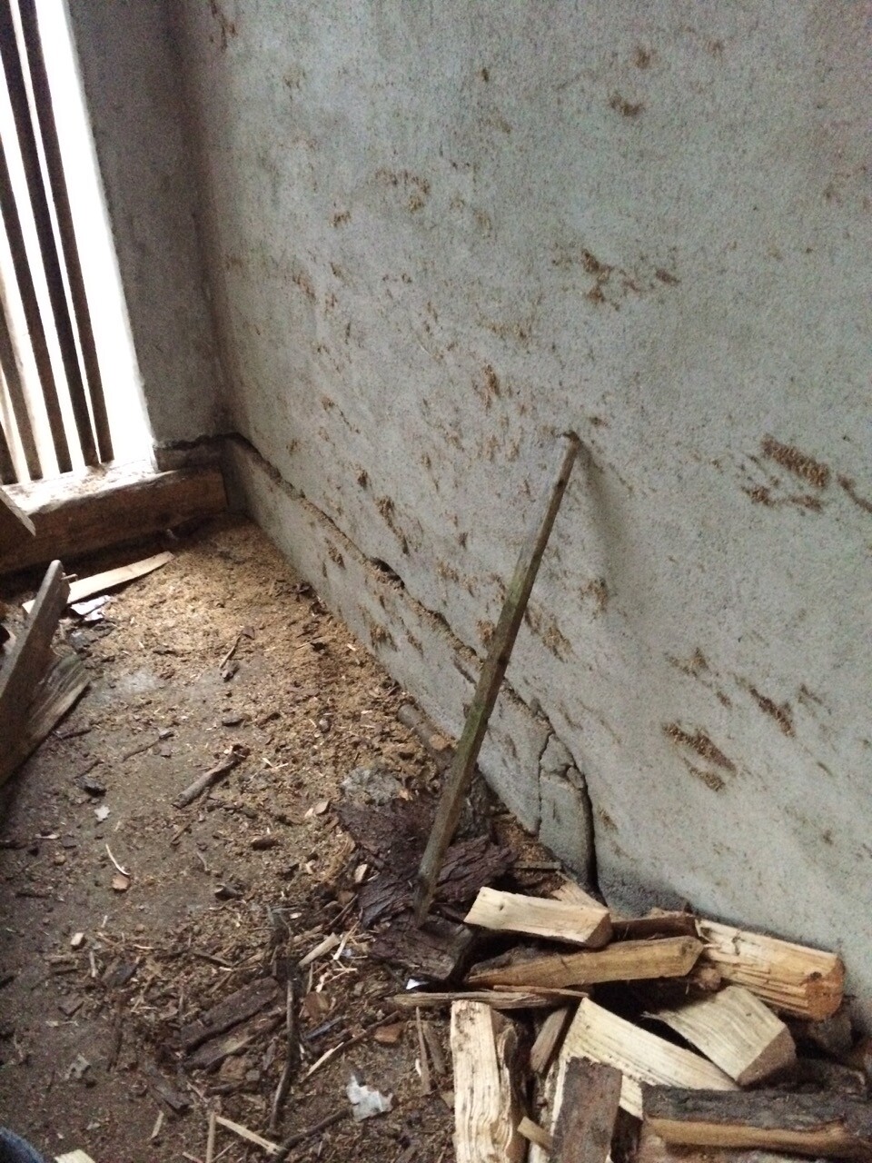 Unfertige Bau-Ecke mit rauer Betonwand, Holzresten und Baustaub am Boden.