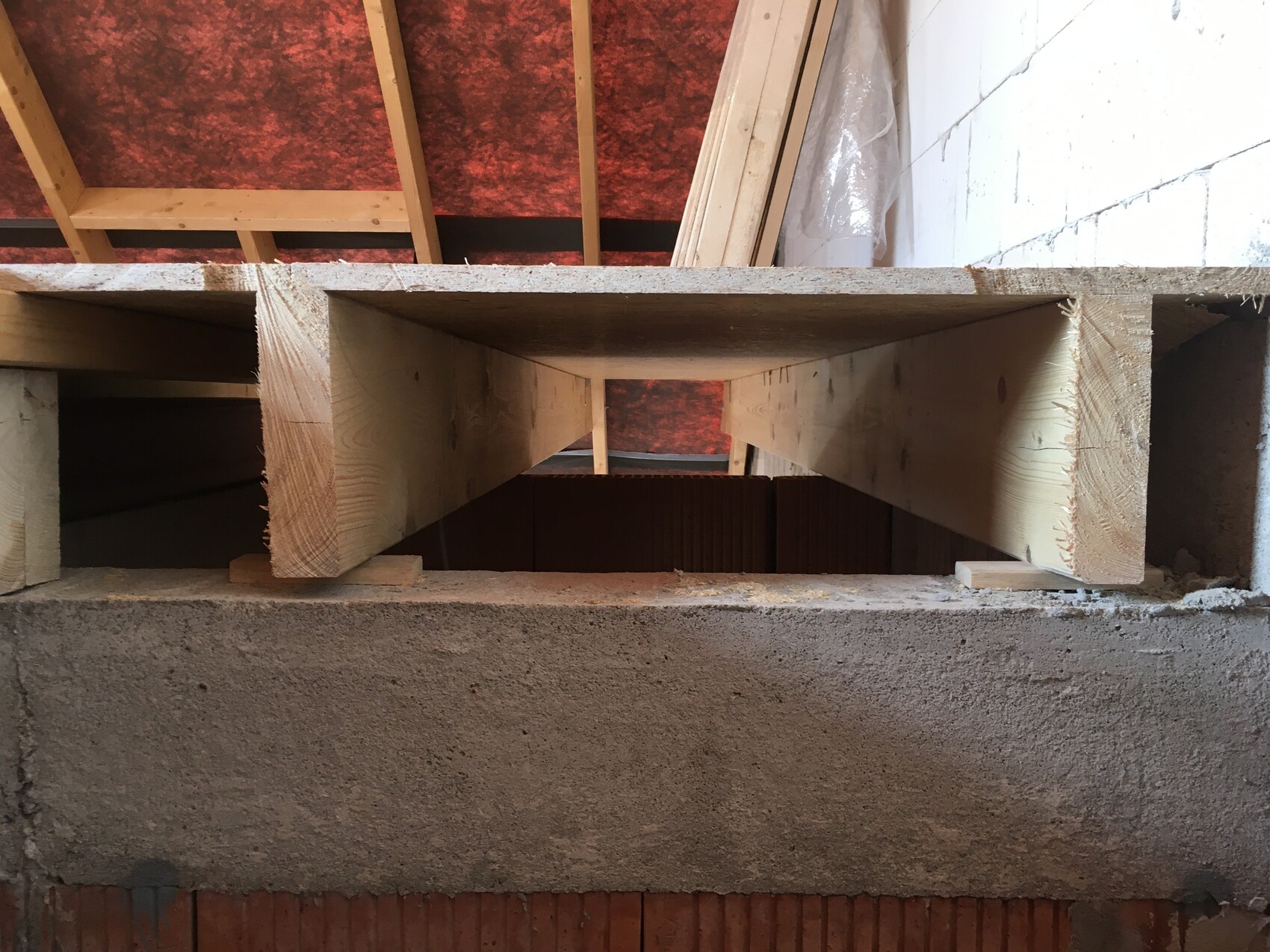 Blick durch eine Holzform auf den rechteckigen Hohlraum einer Kellerdecke zwischen Balken.