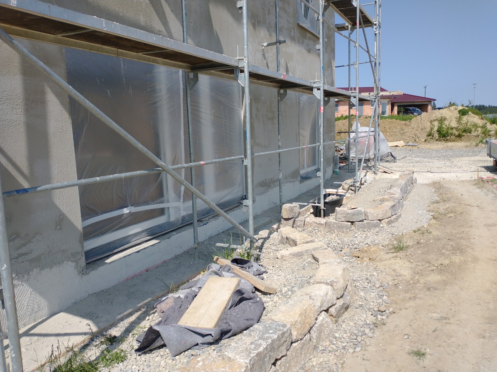 Außenansicht eines unfertigen Rohbaus mit Gerüst und Baumaterial auf einer Baustelle