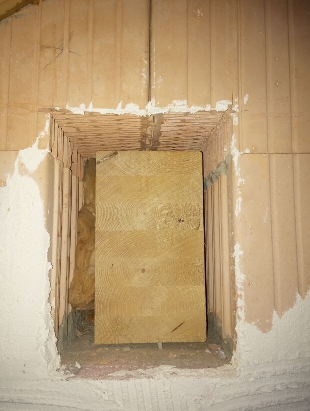 Hohlraumöffnung in gemauerter Wand mit Holzbretter-Provisorium im Rohbau