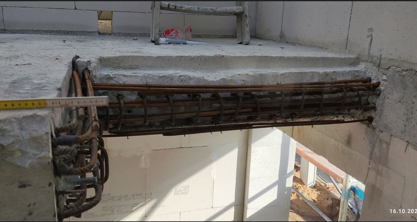 Bewehrter Stahl (Drahtbinder) in einem Betonträger; Messband liegt darauf.