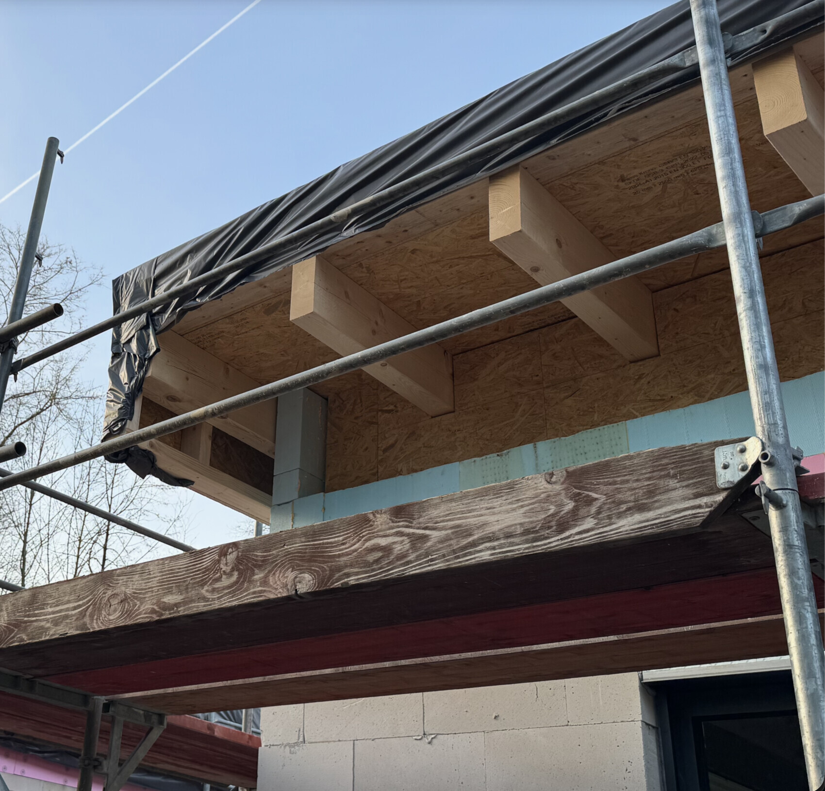 Baustelle am Rohbau mit Holzbalken, OSB-Platten und Gerüstrahmen