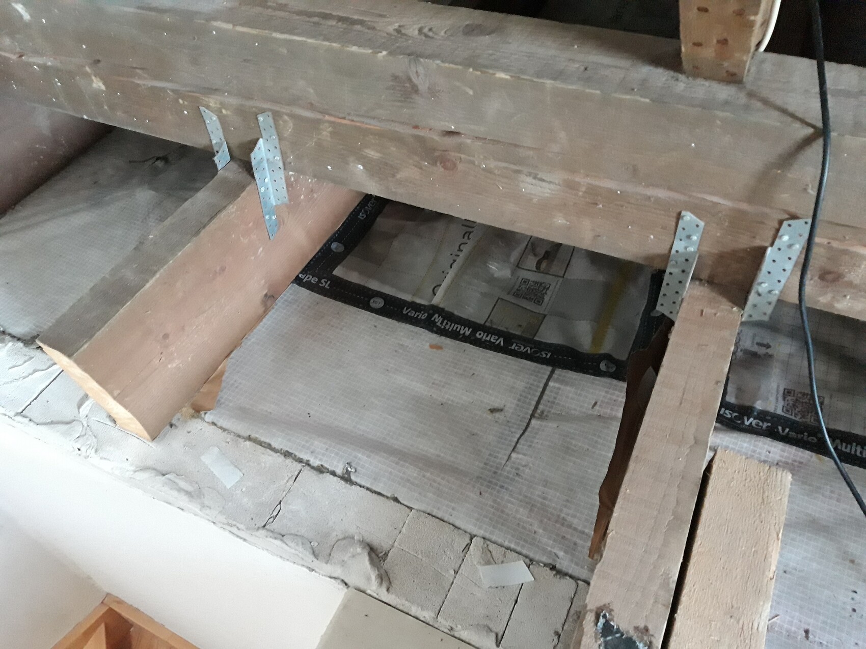 Holzbalken-Deckenlage mit Metallträgern und Dämmung im Rohbau-Bereich