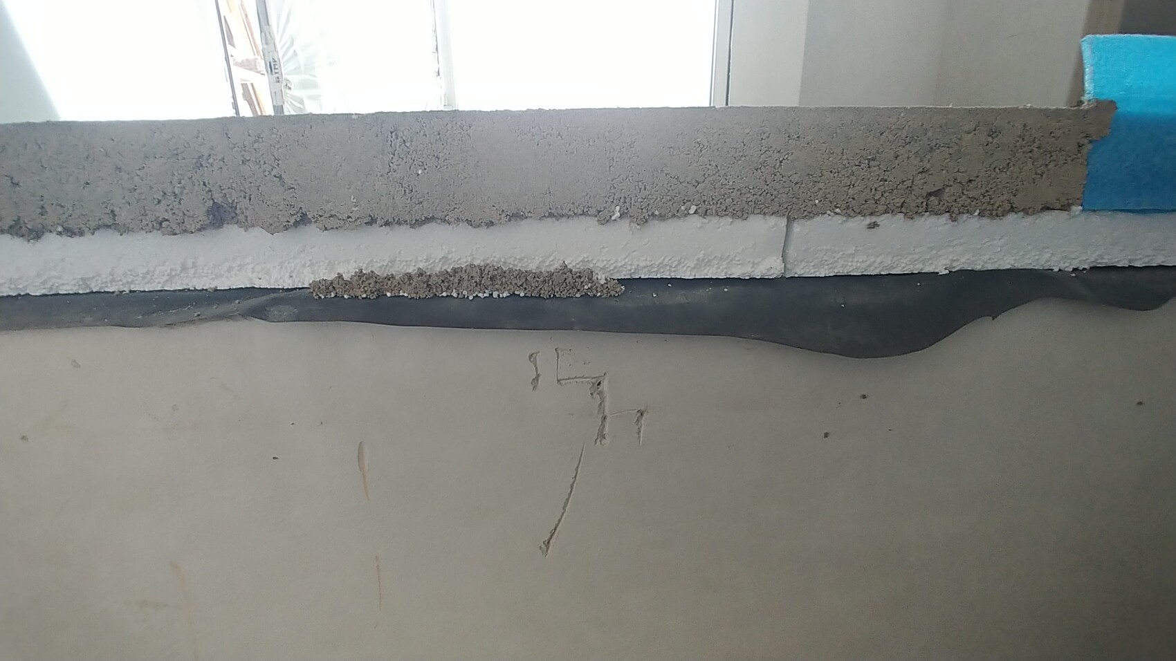 Baustellenaufbau einer Wand mit grobem Beton, Dämmung und Folie in Bauphase