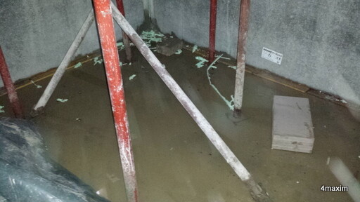 Keller-Rohbau mit Wasserlache, Stahlstützen und unfertigen Wänden
