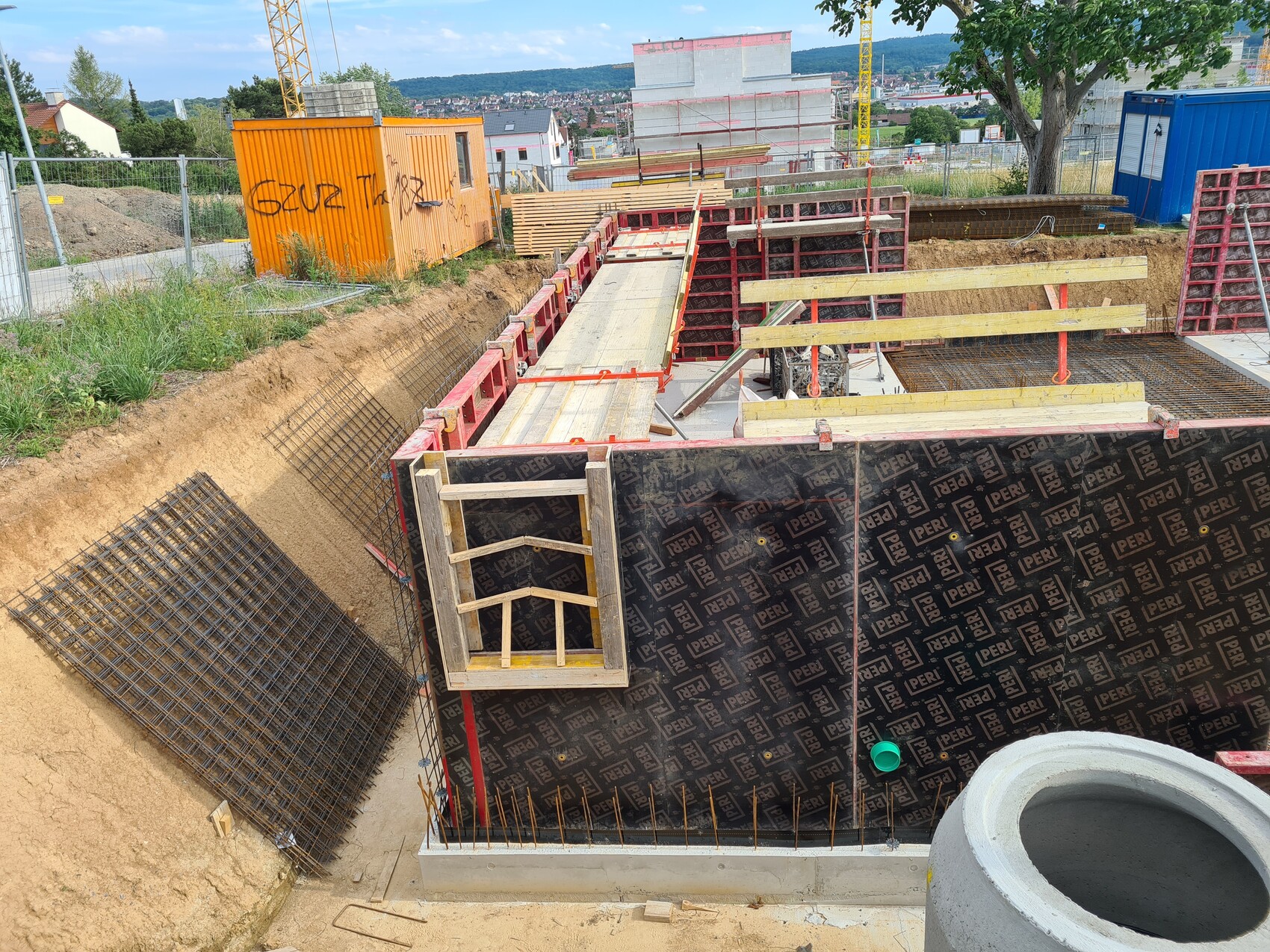 Baugrube mit Schalung, Bewehrung und Holzplanken auf Baustelle.