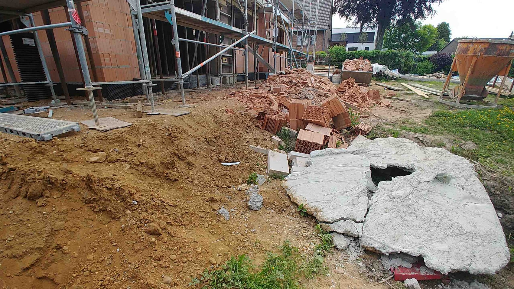 Baustelle mit Gerüst, Baumaterialien aus Ziegeln und grobem Betonfundament.