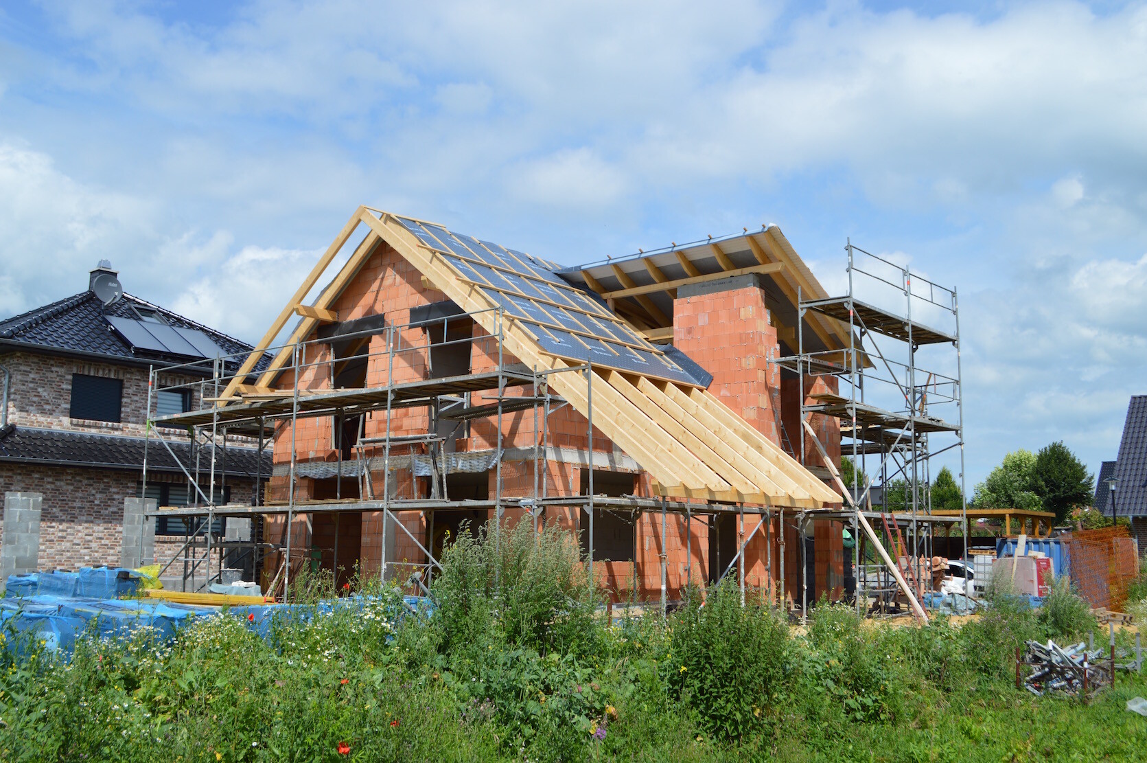 Rohbau eines Hauses mit Gerüst, Ziegelwänden und Dachkonstruktion auf Baustelle