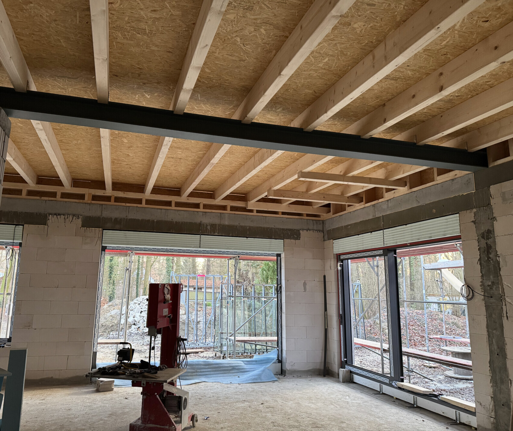 Baustelle: Innenraum mit Holzbalkendecke, Stahlträger und Fensterfronten