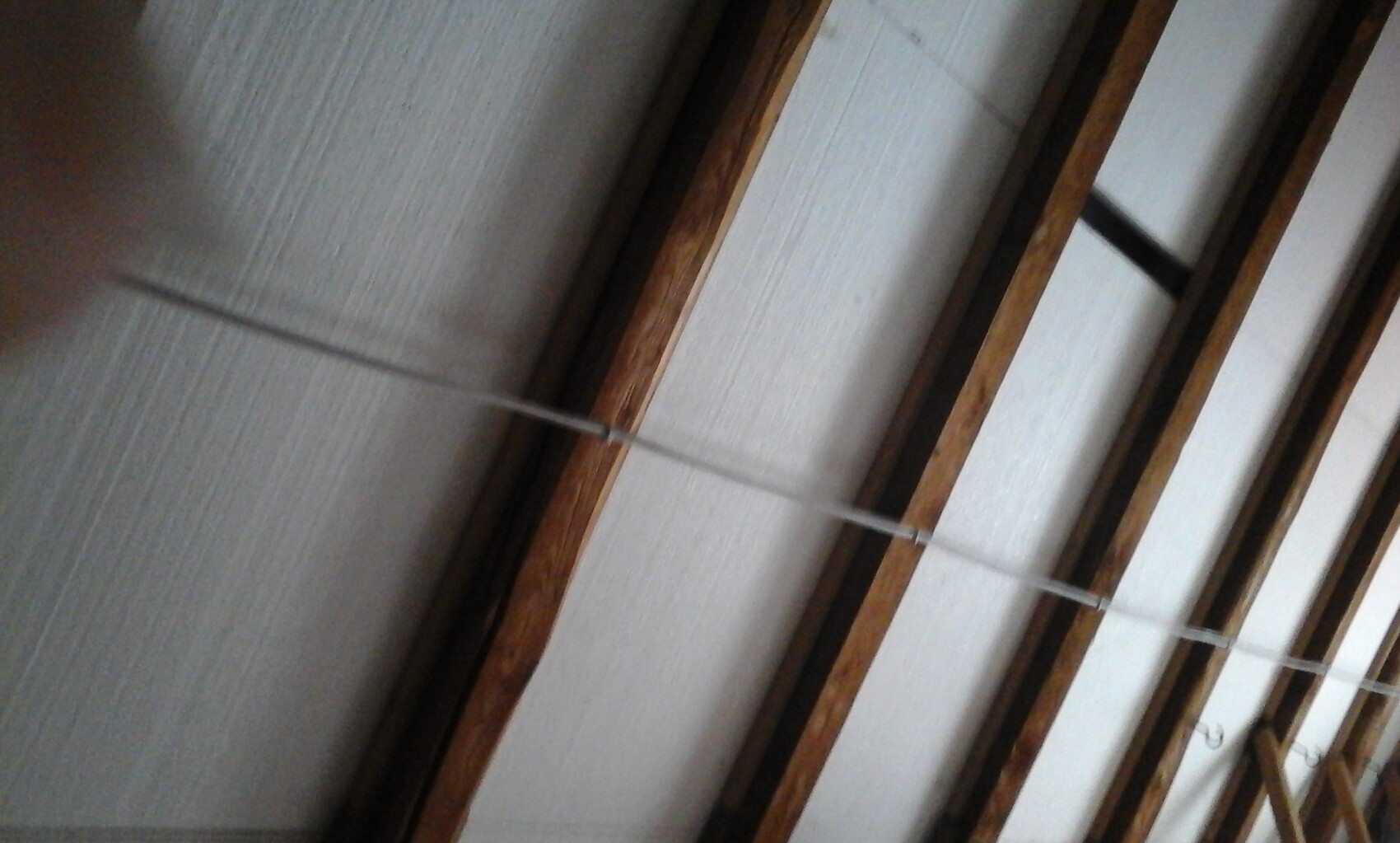 Rohbau-Decken mit Holzbalken und sichtbaren Seilen in einem Arbeitsbereich