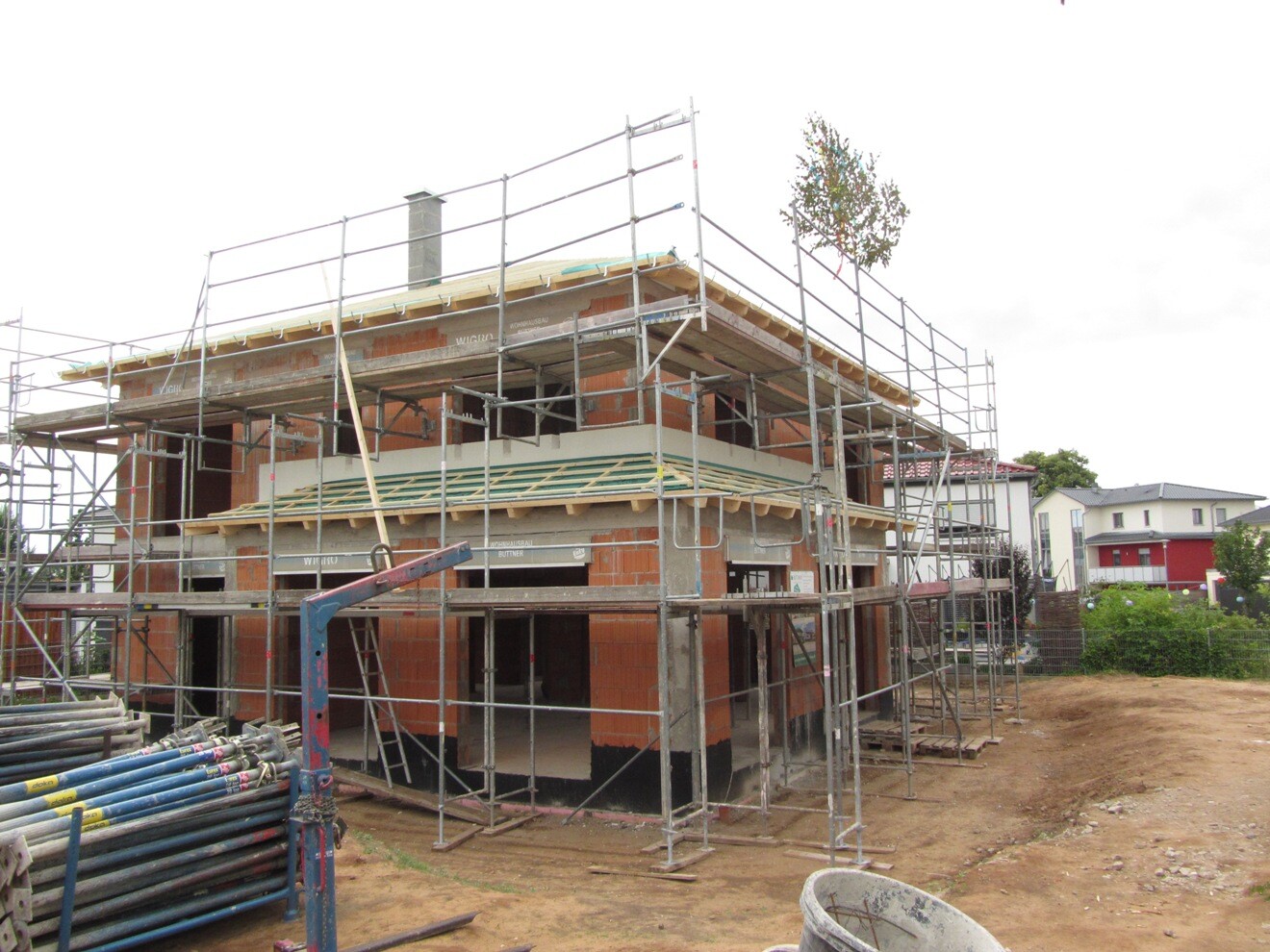 Rohbau eines zweistöckigen Hauses mit Gerüst und Baumaterialien.
