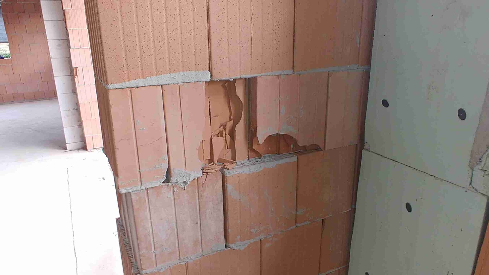 Unverputzte Rohbauwand aus Ziegeln mit Mörtel und beschädigten Bereichen im Bau