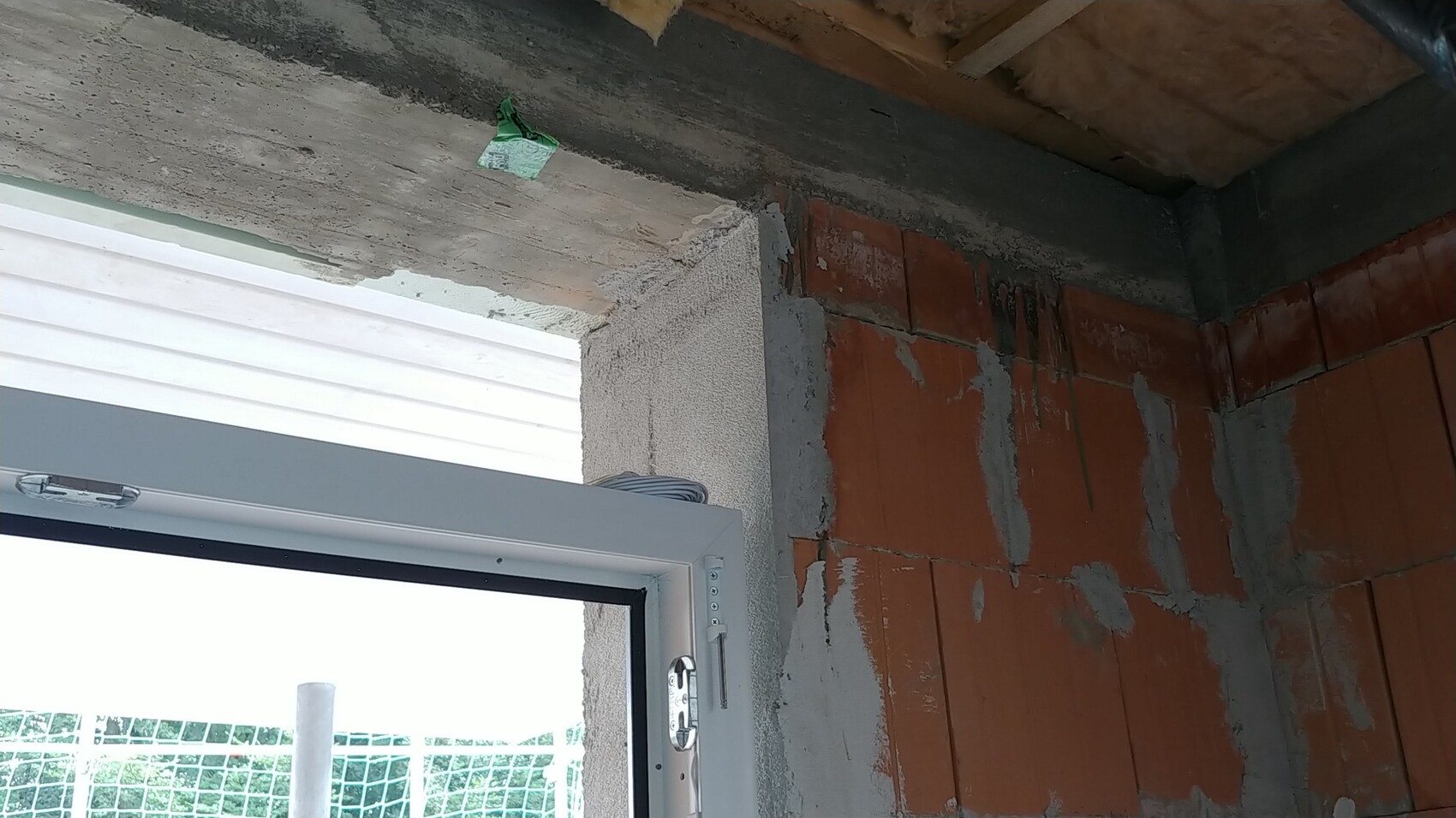 Unverputzte Innenwand aus Ziegeln neben Fensterrahmen im Rohbau